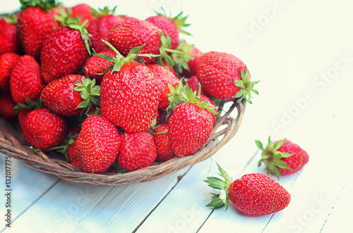 Strawberry in wicker plate on wooden background