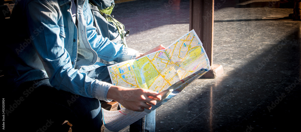 Fototapeta premium Traveler sitting and looking in map for waiting train at train station. Travel concept by train with vintage tone.