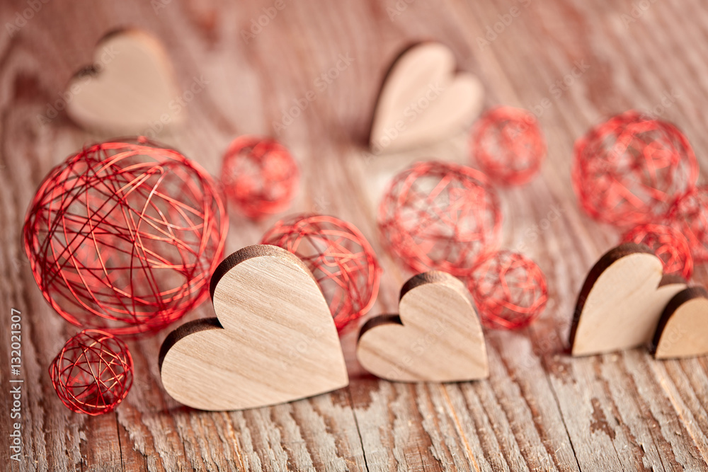 Different size heart figures on wooden background with bauble