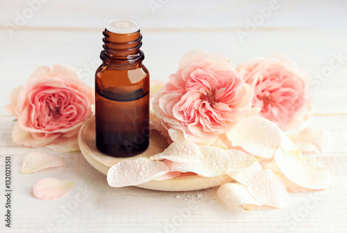 Rose aromatherapy. Essential oil dark glass apothecary dropper bottle, fresh flower petals. Handcrafted botanical beauty care. 