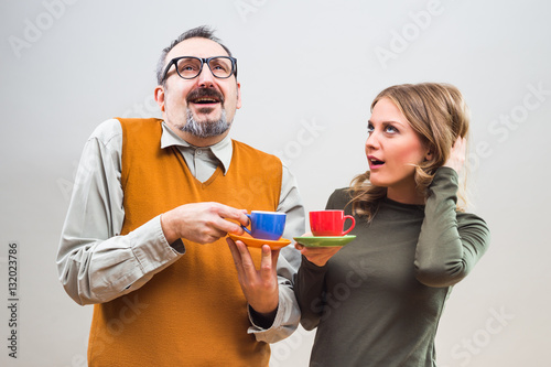 Funny nerdy man and beautiful woman enjoy drinking coffee.