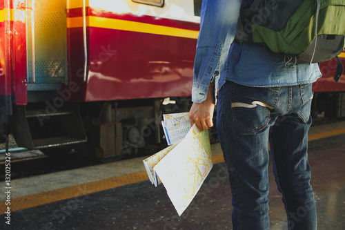 Young man holding map standing on platform at train station for travel. Travel concept by train.
