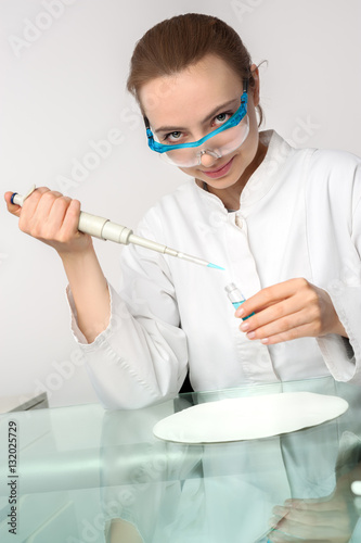 Young female tech or scientist works with automatic pipette