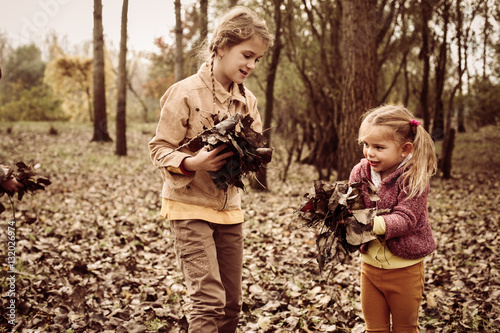 Children playing in fall leaves. © liderina