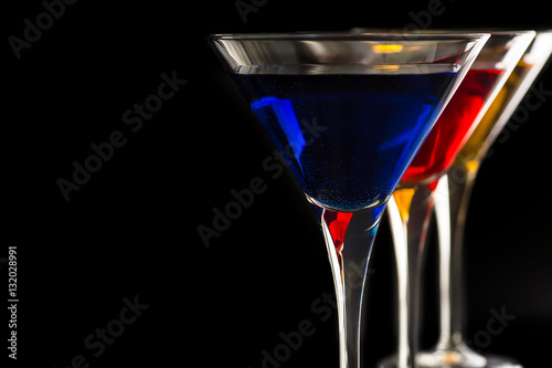 Colorful Cocktails in Martini Glasses on Black Background. Bar Commercials Concept.