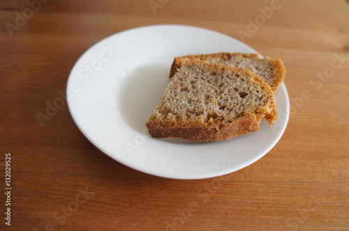Two piece of bread in white plate in wooden table 