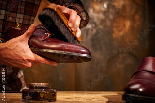 Foto Man polishing leather shoes with brush