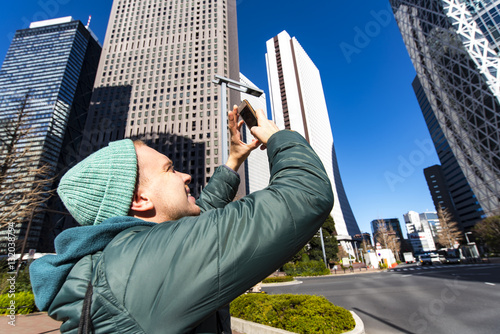 Photography A tourist taking picture by phone of business architecture in Tokyo, Japan