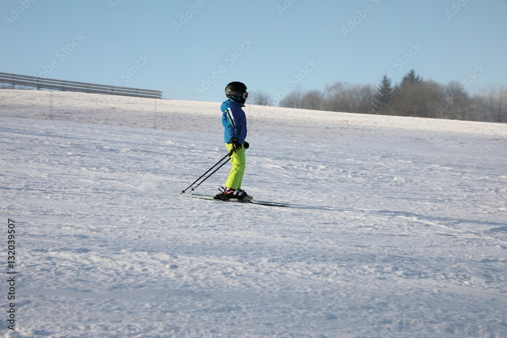 Fototapeta premium Little skier on the piste with a helmet on his head. Suitable for promotional use, instead of the headline.