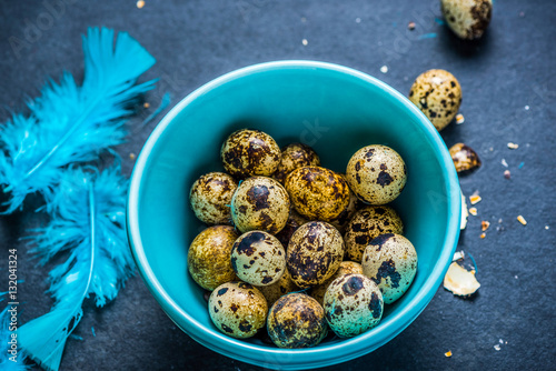 Quail eggs in pastel bowl on dark background, Easter concept.