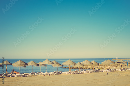 Holiday and vocation image with sandy beach, parasol and chairs on outdoors background