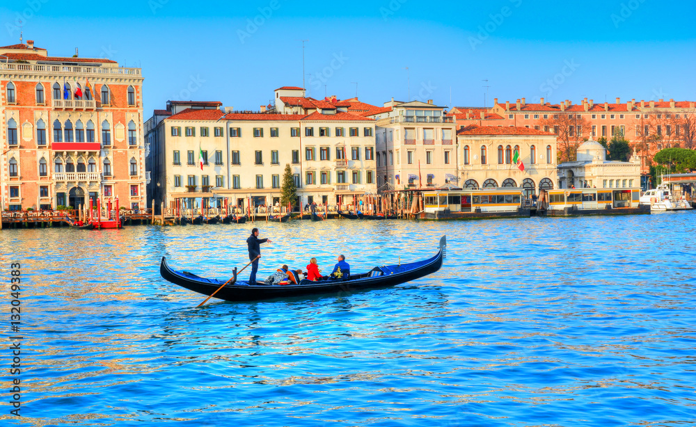 Traditional gondola transporting tourists on the famous Grand Canal, in Venice - Italy