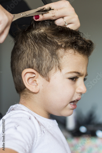 Little kid protests when his mother cuts his hair