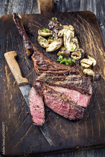 Barbecue Tomahawk Steak mit Pilzen auf Schneidebrett photo