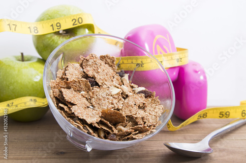 bowl of cereal with fruit, weights and tape measure and concept of diet and healthy living