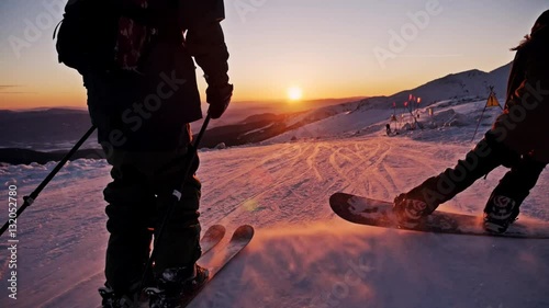 Slowmotion footage of a skier and snowboarder riding the slope during a beautiful sunset. photo
