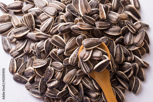 Obraz na plátně Sunflower seeds and a wooden spoon on a white background