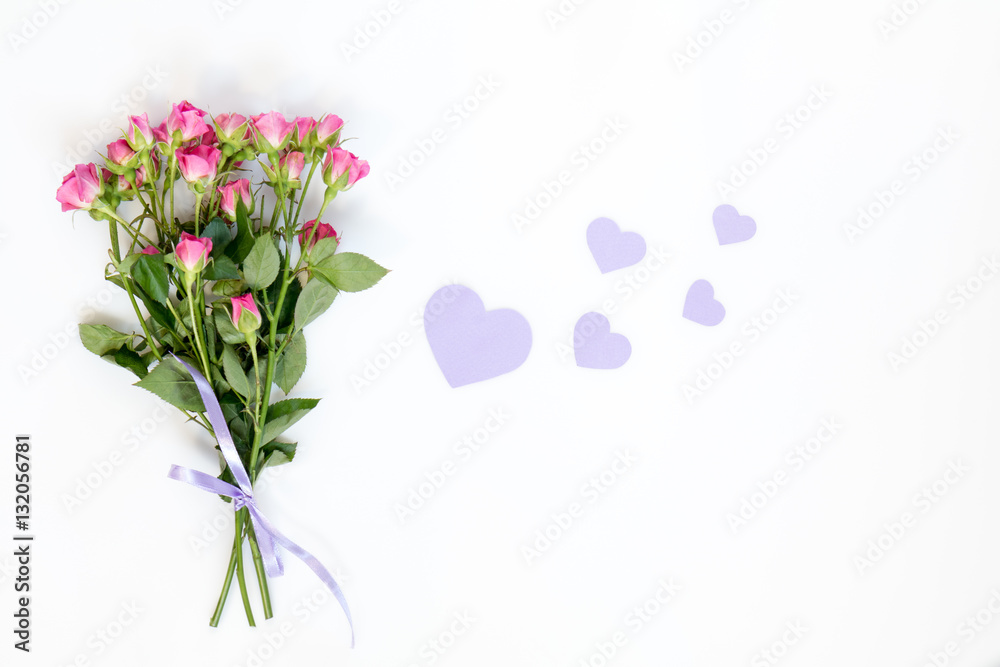 Fresh pink little roses and paper violet hearts. Flat lay on white background, top view. Fresh pink little roses and paper violet hearts. Flat lay on white background, top view.