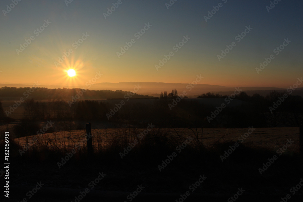 Stimmung bei Sonnenaufgang über Feldern im Winter