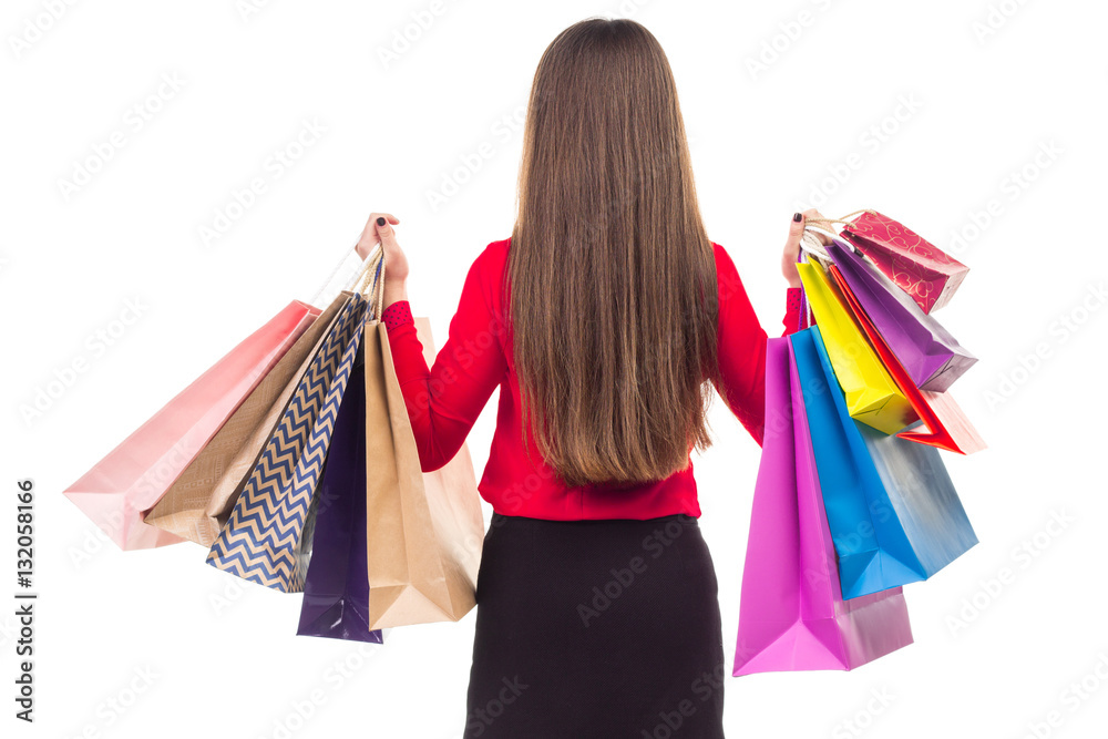 Long-haired girl from back holds versicolored shopping paper bag