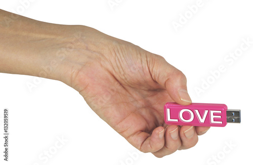 A USB filled with Information on Love - female hand holding out a pink USB stick with LOVE engraved in white on the side, isolated on a white background