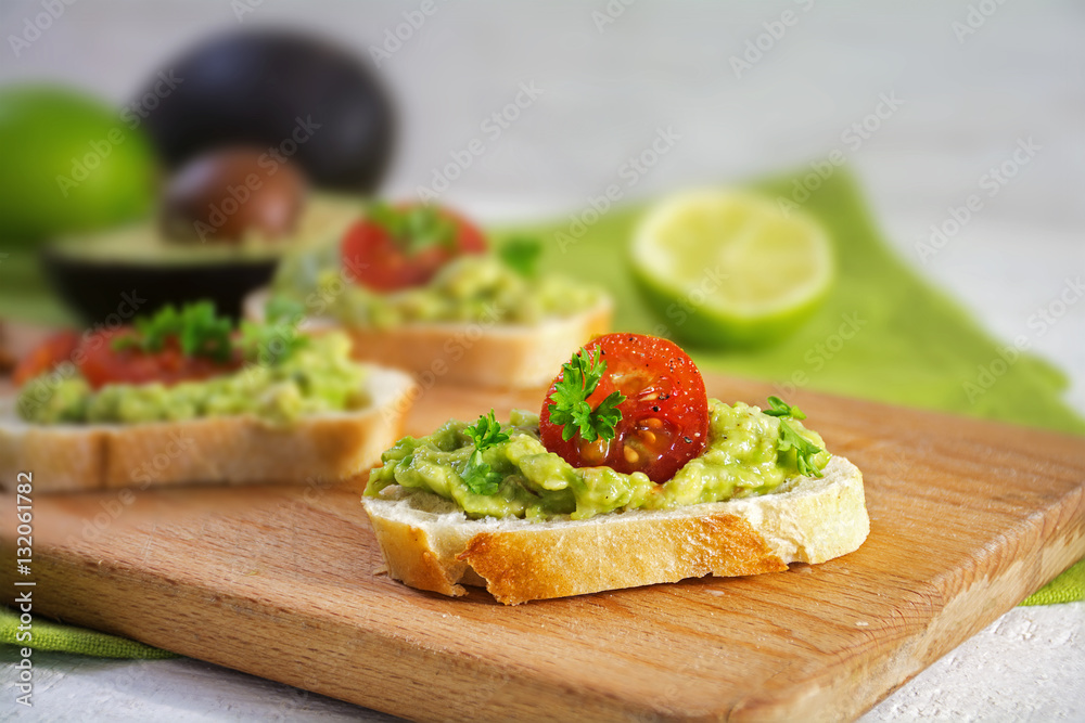 Canape sandwich with avocado cream or guacamole and tomatoes on a kitchen board