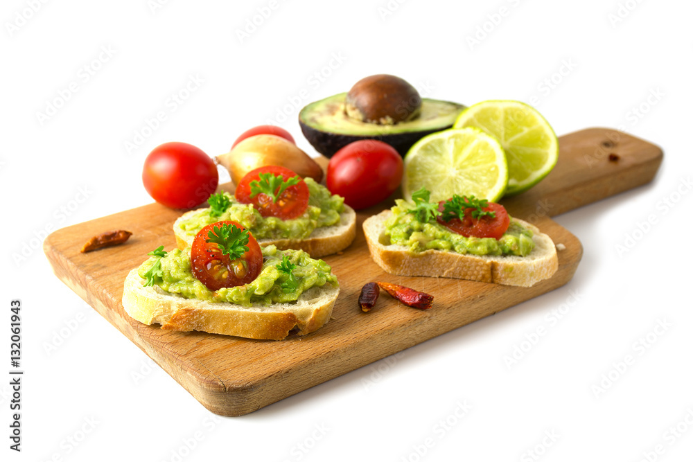 Canapes with avocado cream or guacamole, tomatoes and ingredients on a wooden board, isolated on white Canapes with avocado cream or guacamole, tomatoes and ingredients on a wooden board, isolated on white