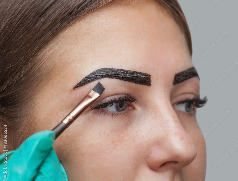 makeup artist applies paint henna on previously plucked, design, trimmed eyebrows in a beauty salon in the session correction. Professional care for face.