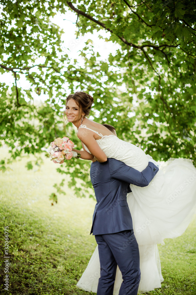 Groom carries his bride over shoulder. Outdoor. Groom carries his bride over shoulder. Outdoor.