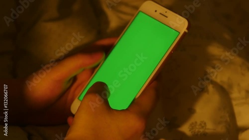 A man uses a green screen smart phone on bed photo