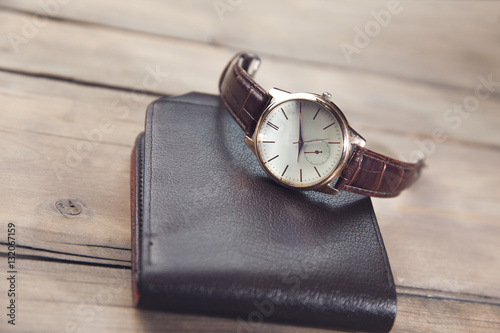 elegant watch and wallet on wooden table