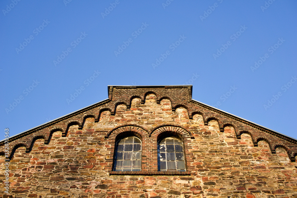 Historisches Fabrikgebäude mit Bruchsteinfassade und Bogenfenstern. Bild mit Textfreiraum