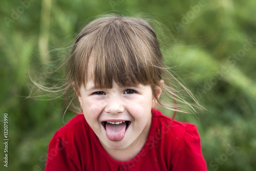 фотографія Smiling little girl shows tongue. Young cute little girl gesturi