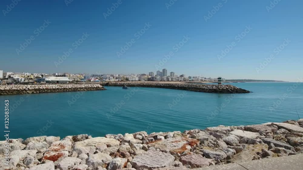 Aerial. Video pier fishing port, ship sails into the bay, town Quarteira. Aerial. Video pier fishing port, ship sails into the bay, town Quarteira.