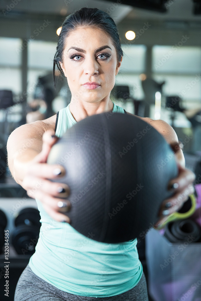 Strong, healthy woman holding heavy medicine ball in gym workout