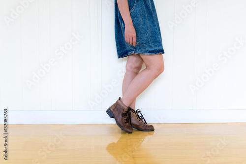 Women wearing boots brown skirt standing against the wall