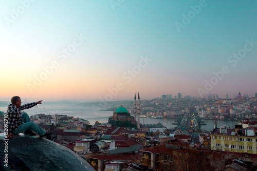 Canvas Print Silhouette of traveler sitting on top of building and city view