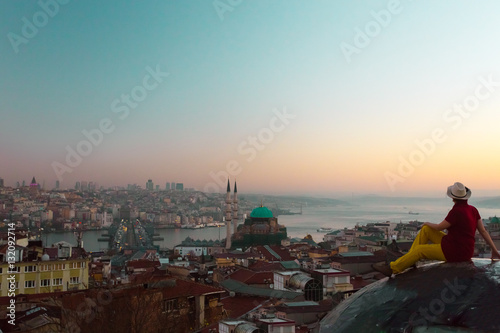 Lady in vintage Hat sitting on roof of building and overlooking city