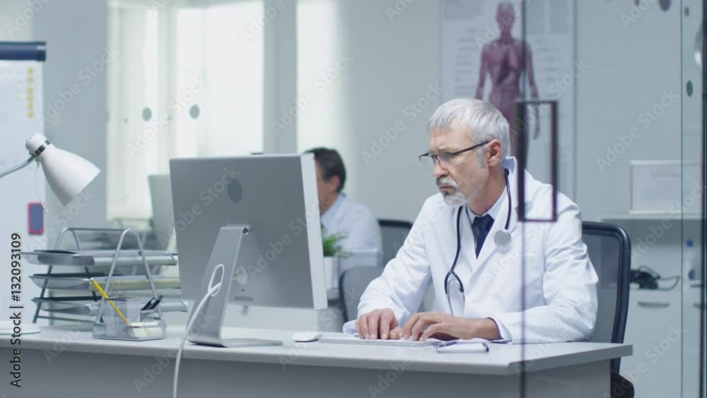 Senior Doctor and His Assistant Working on PC in Bright and Light Office. Shot on RED Cinema Camera in 4K (UHD). Senior Doctor and His Assistant Working on PC in Bright and Light Office. Shot on RED Cinema Camera in 4K (UHD).