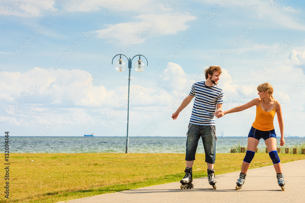 Fototapeta premium Young couple on roller skates riding outdoors