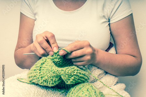 Woman hands with needles knitting with green wool
