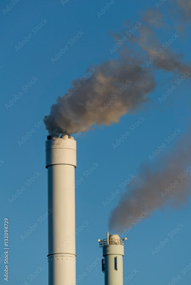 polluted smoke against a clear blue sky from the tall chimney