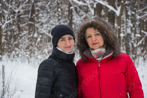 senior woman mother with daughter in winter in the snow wood smiling