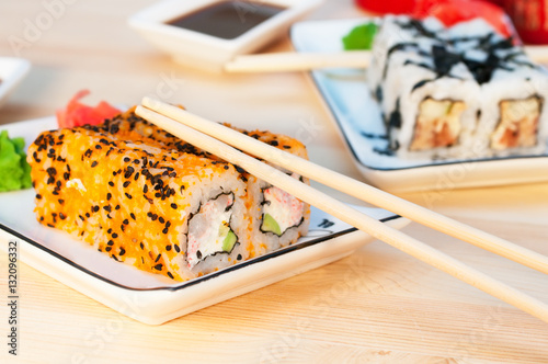 Sushi rolls on the white plate on wooden background
