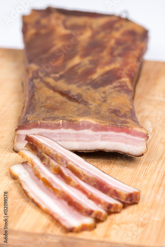 Sliced raw smoked bacon on the wooden board