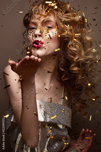 Beautiful girl in an evening dress and gold curls. Model in New Year's image with glitter and tinsel. Holiday picture. Christmas atmosphere.