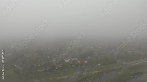 Airplane is cutting through thick clouds and    approaching Manchester airport near Stockport,  England, UK. City and infrastructure view from inside of landing aircraft. photo