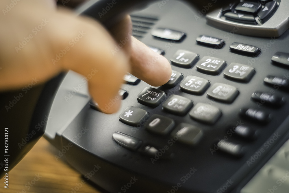 businessman dialing voip phone in the office, keyboard and monitor detail in the background with vintage color tone effect businessman dialing voip phone in the office, keyboard and monitor detail in the background with vintage color tone effect