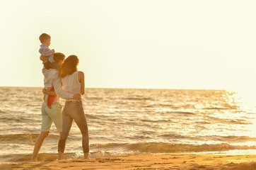 happy young family have fun on beach run and jump at sunset