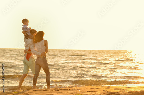 happy young family have fun on beach run and jump at sunset